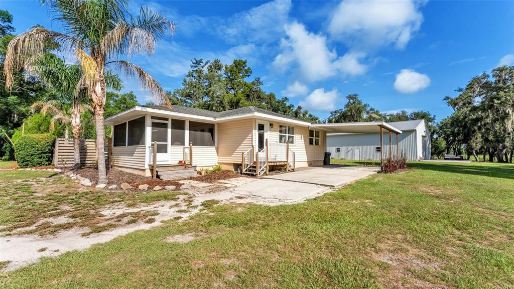 A single-story house with light siding, a screened porch, and an attached carport — 5275 GREEN POND ROAD, POLK CITY, FL