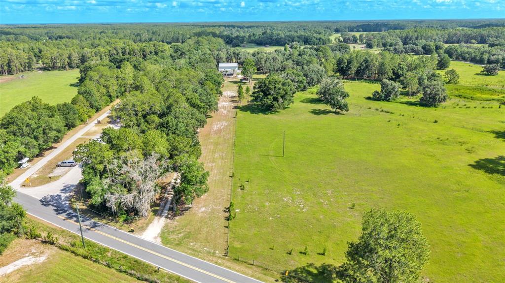 An aerial view shows a rural property with a road, trees, and open pasture land — 5275 GREEN POND ROAD, POLK CITY, FL