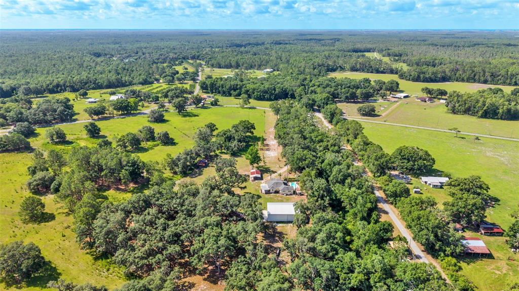 An aerial view shows a rural property with a house, outbuildings, and surrounding wooded land — 5275 GREEN POND ROAD, POLK CITY, FL