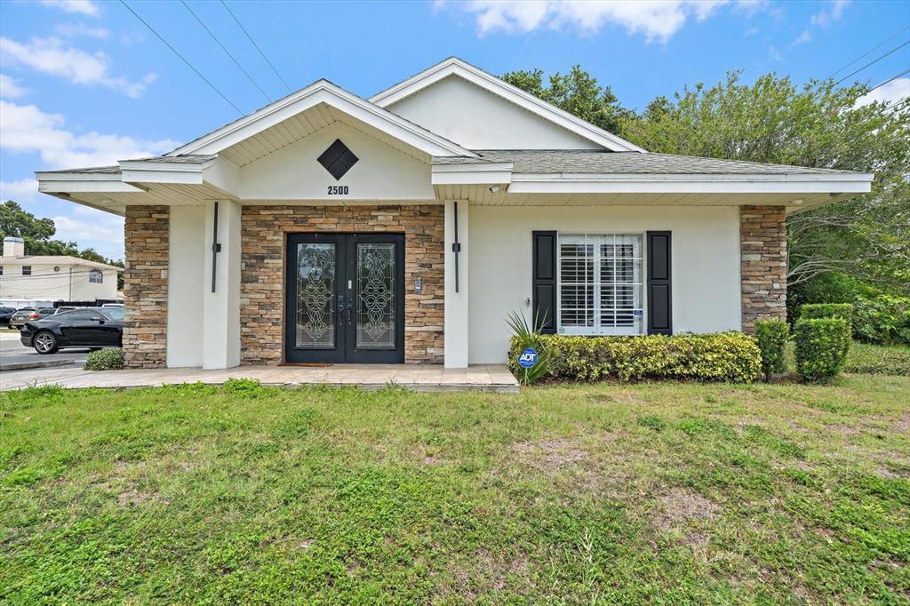A single-story building features a stone facade, double glass doors, and a white exterior — 2500 SUNSET POINT ROAD, CLEARWATER, FL