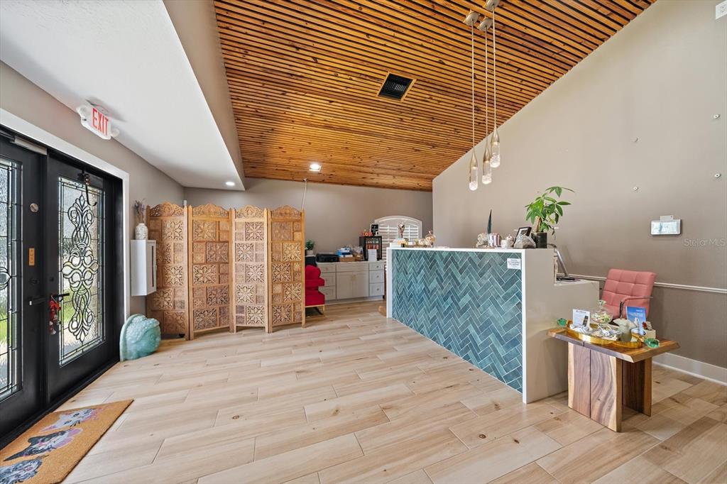 A reception area features a wood-slat ceiling, a tiled front desk, and light wood flooring — 2500 SUNSET POINT ROAD, CLEARWATER, FL