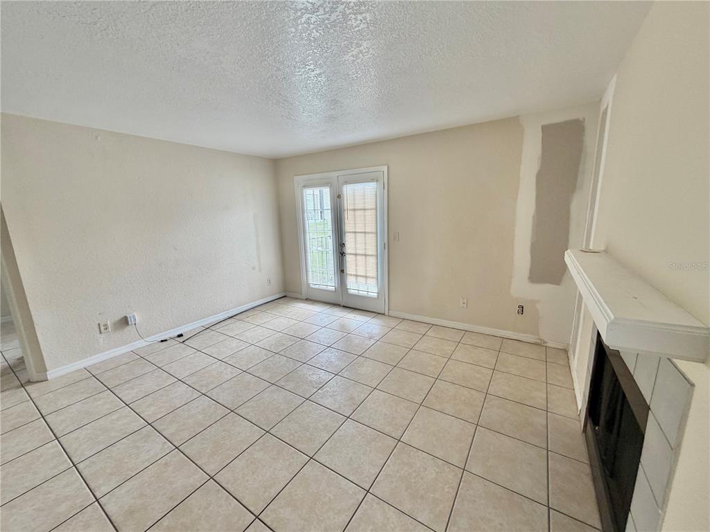 A living room features beige tile flooring, a fireplace, and glass French doors — 2550 N ALAFAYA TRAIL UNIT 3103, ORLANDO, FL