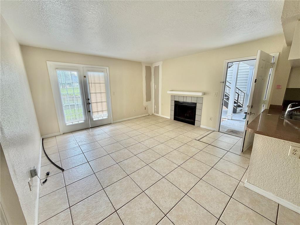 A tiled living room features a fireplace, French doors, and an open doorway to outside — 2550 N ALAFAYA TRAIL UNIT 3103, ORLANDO, FL