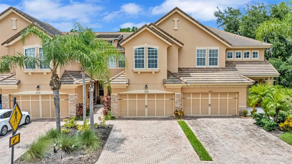 A multi-unit residential building with tan stucco walls, tiled roofs, and paved driveways — 8228 VILLA GRANDE COURT, SARASOTA, FL
