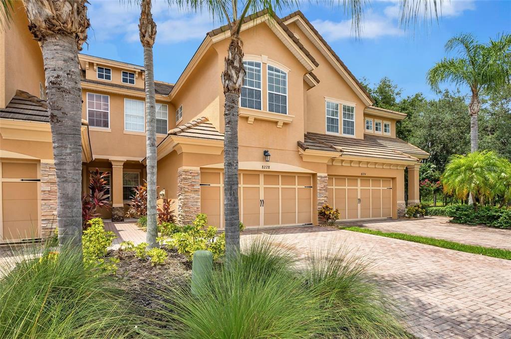 A two-story tan stucco house features a multi-car garage and a paved driveway — 8228 VILLA GRANDE COURT, SARASOTA, FL