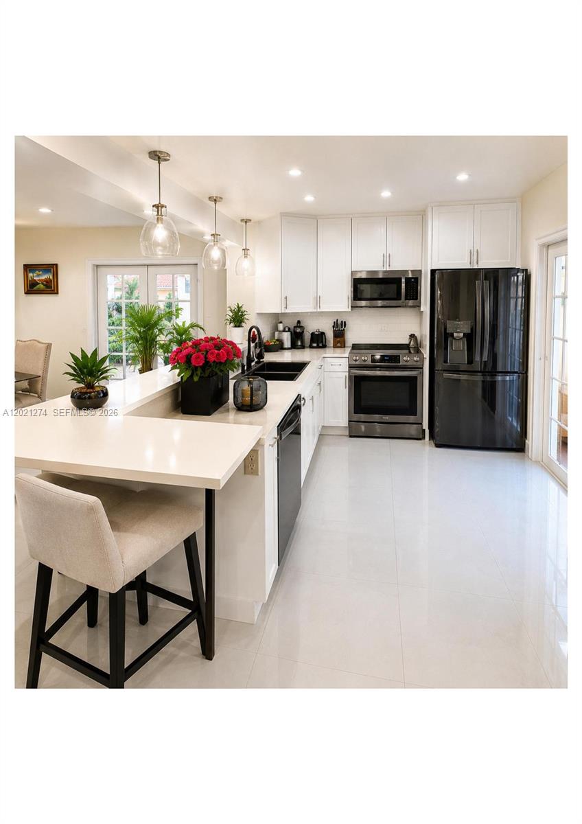 A modern kitchen features white cabinets, stainless steel appliances, a black refrigerator, and a peninsula — 8265 NW 6th Ter # 251, Miami FL 33126, MIAMI, FL