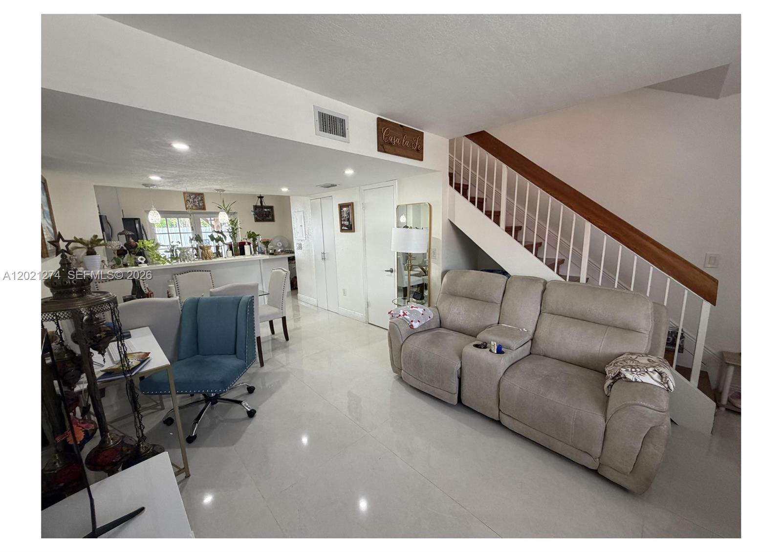A living room features a beige reclining sofa, white tile floors, and a staircase — 8265 NW 6th Ter # 251, Miami FL 33126, MIAMI, FL