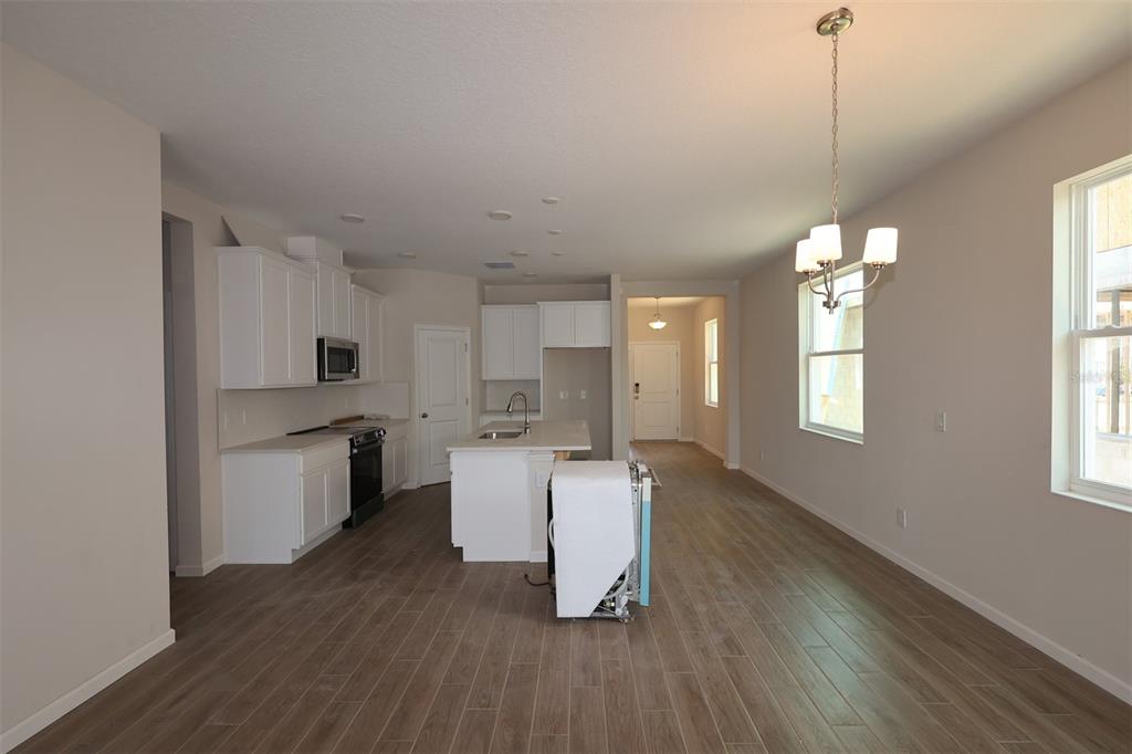 A kitchen with white cabinets, a center island, and wood-look tile flooring — 2679 GREAT HERON AVENUE, ST CLOUD, FL