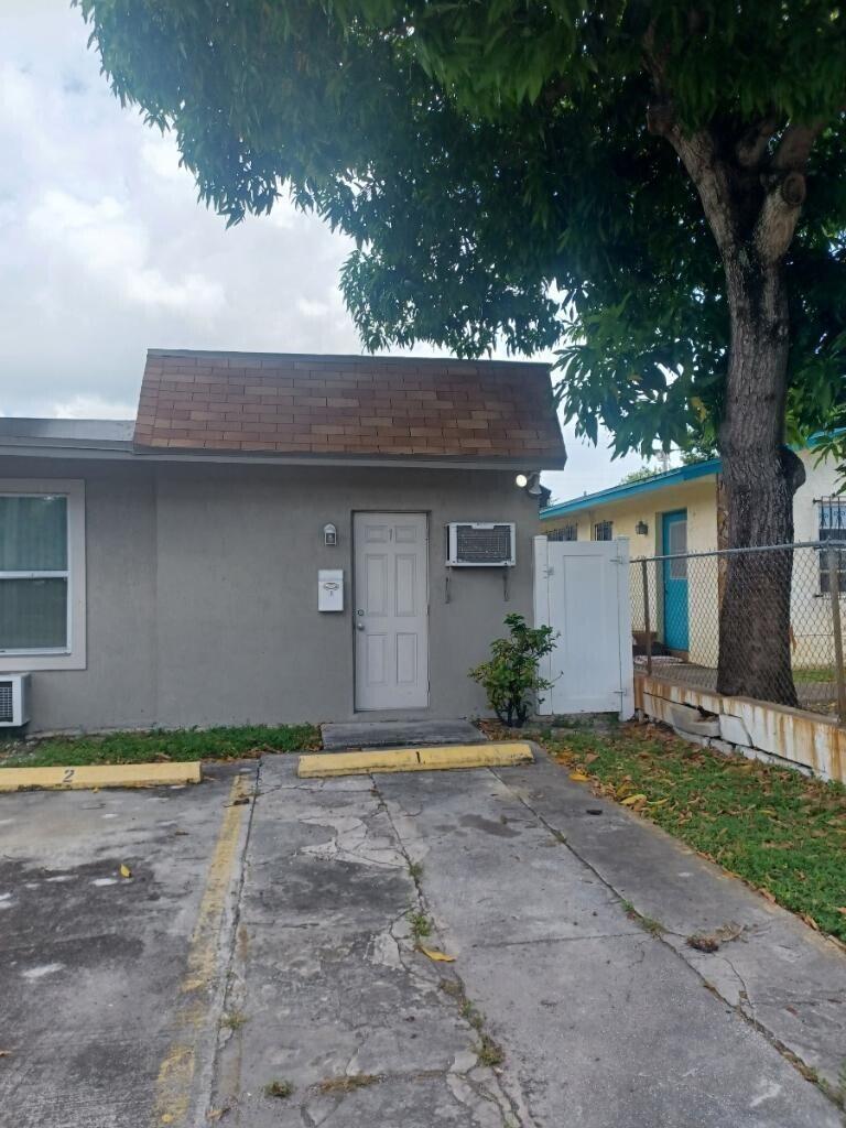 A gray exterior of a single-story unit with a white door and a parking space — 24 SW 13th Street # 5, Dania Beach FL 33004, DANIA BEACH, FL