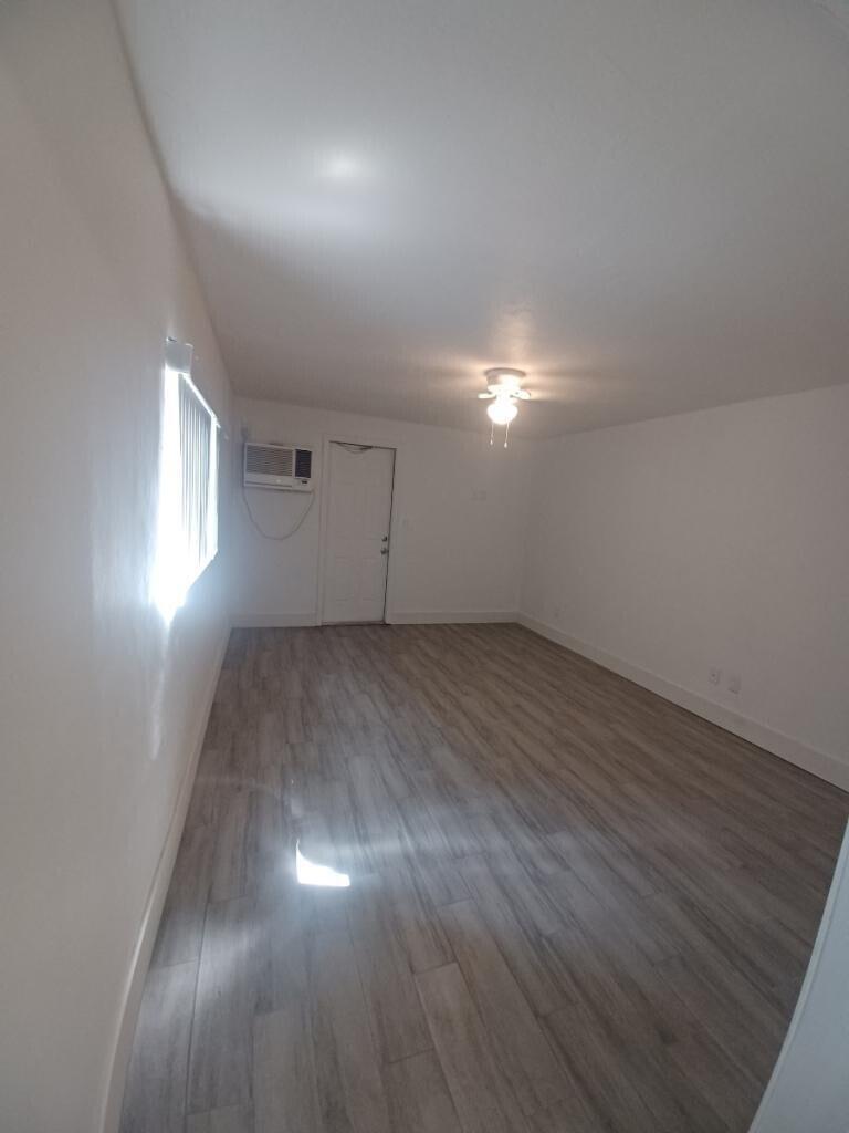 An empty room with light wood-look flooring, white walls, a ceiling fan, and an air conditioner — 24 SW 13th Street # 5, Dania Beach FL 33004, DANIA BEACH, FL