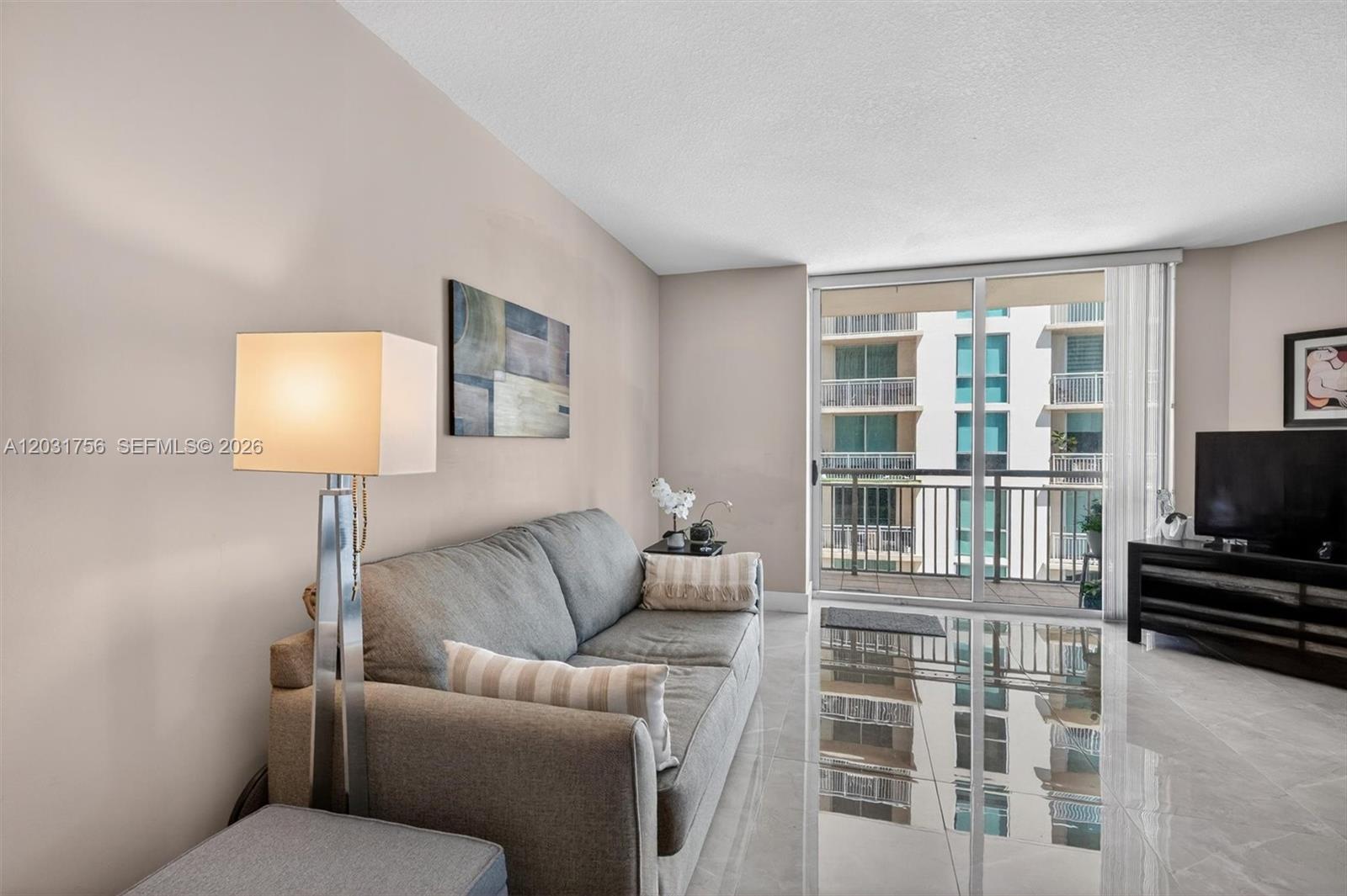 A living room features a gray sofa, a floor lamp, and a balcony with views — 9066 SW 73rd Ct # 1203, Miami FL 33156, MIAMI, FL