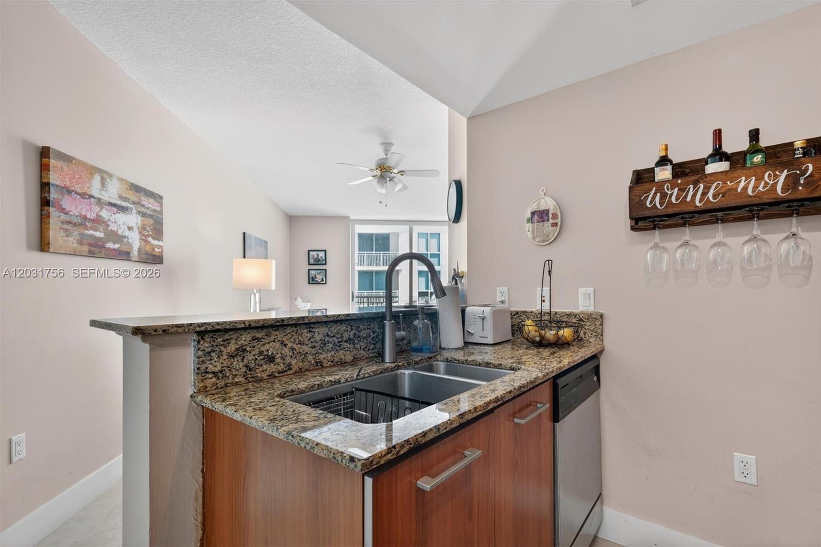 A kitchen sink area features granite countertops, wood cabinets, and a wall-mounted wine rack — 9066 SW 73rd Ct # 1203, Miami FL 33156, MIAMI, FL