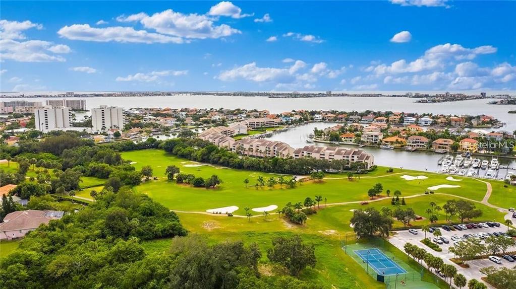 An aerial view shows a golf course, residential buildings, a tennis court, and a marina — 5950 PELICAN BAY PLAZA S UNIT 505, GULFPORT, FL
