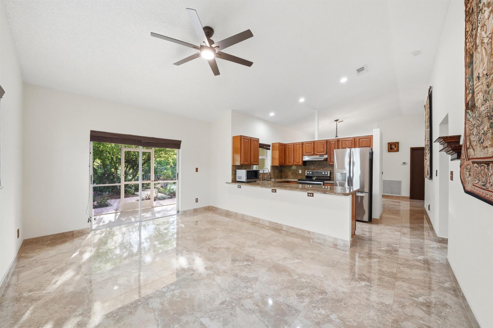 An open-concept kitchen and living area features marble tile flooring and a sliding glass door — 5787 SW 57th Way, Davie FL 33314, DAVIE, FL