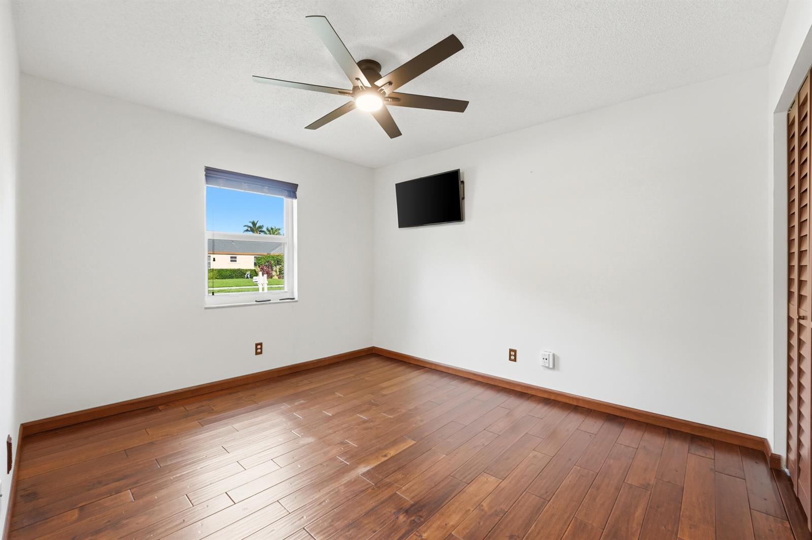 An empty bedroom features white walls, dark wood flooring, a ceiling fan, and a wall-mounted television — 5787 SW 57th Way, Davie FL 33314, DAVIE, FL