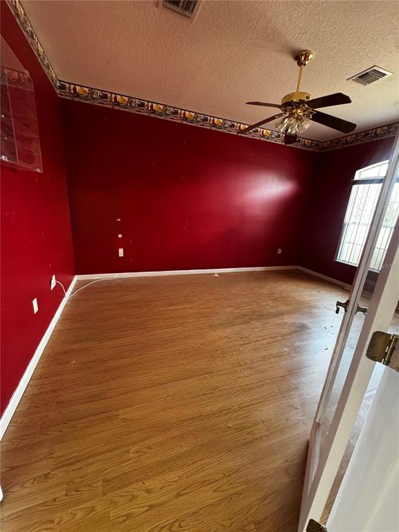 An empty room features red walls, a ceiling fan, and wood-look laminate flooring — 15296 SW 15TH TERRACE ROAD, OCALA, FL