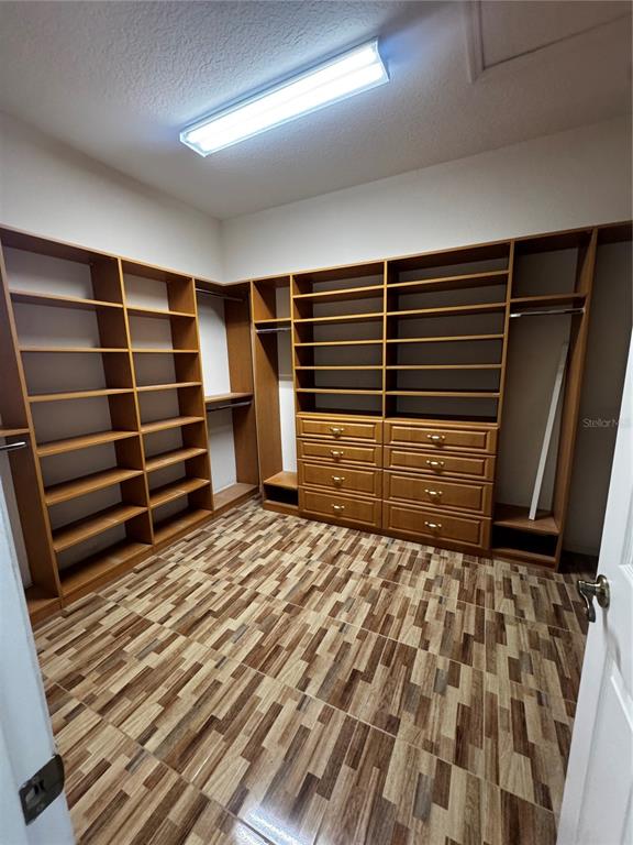 A walk-in closet features wood shelving, built-in drawers, and patterned tile flooring — 15296 SW 15TH TERRACE ROAD, OCALA, FL