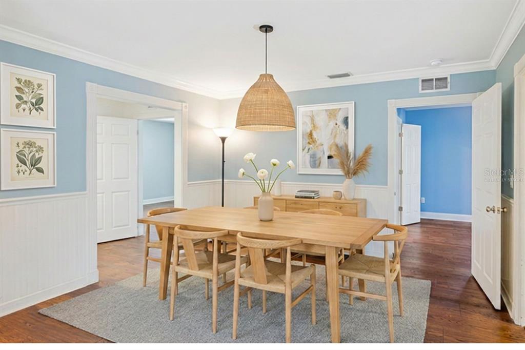 A dining room with light blue walls, white wainscoting, a wooden table, and woven chairs — 201 S SHERRILL STREET, TAMPA, FL