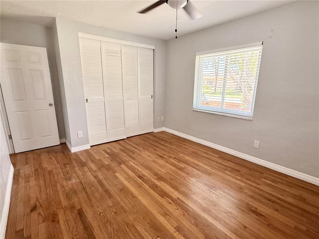 An empty living room features light-colored walls, wood-look flooring, a ceiling fan, and a window — 4320 YARDLEY AVENUE N, ST PETERSBURG, FL
