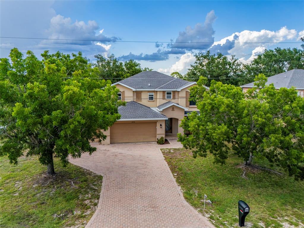 A two-story house with a paved driveway, a two-car garage, and mature trees — 25134 PALISADE ROAD, PUNTA GORDA, FL
