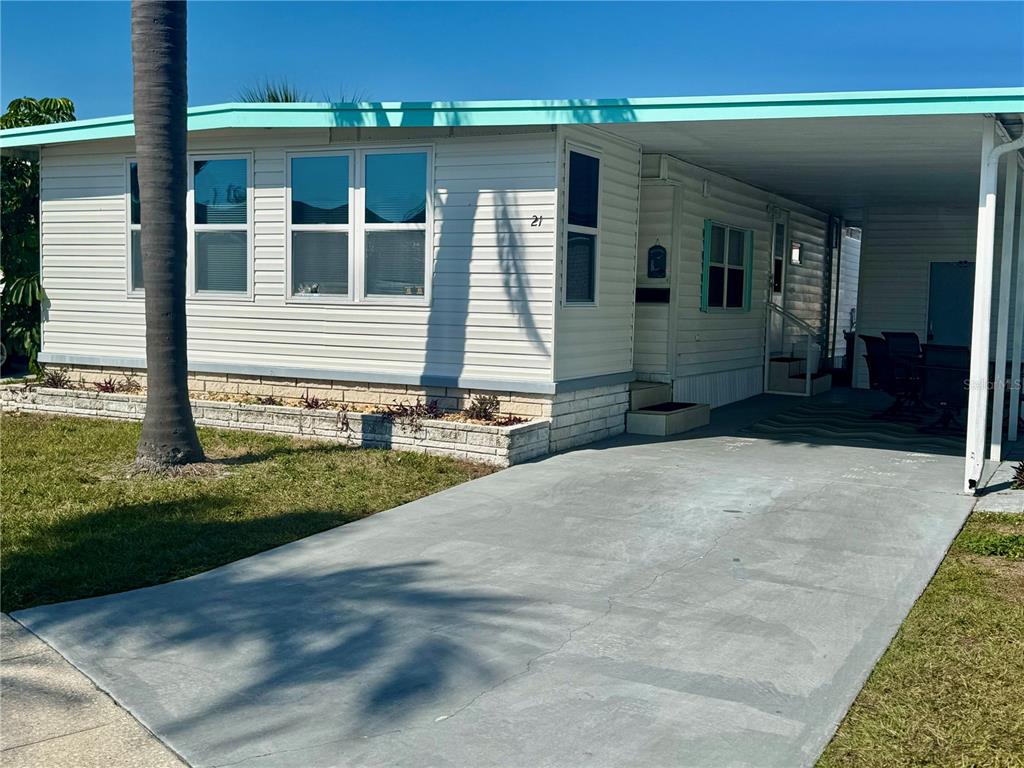 A single-story mobile home with white siding, a turquoise roofline, and an attached carport — 7901 N 40TH AVENUE N UNIT 21, ST PETERSBURG, FL