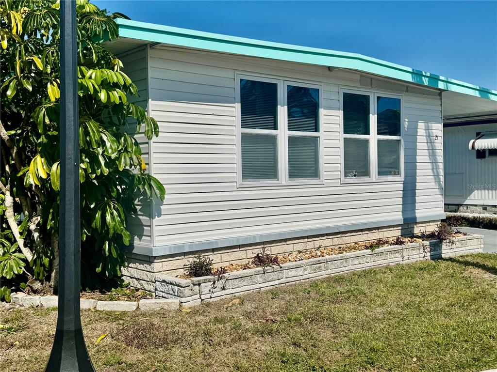 The exterior of a light-colored mobile home features horizontal siding, a turquoise roofline, and windows — 7901 N 40TH AVENUE N UNIT 21, ST PETERSBURG, FL