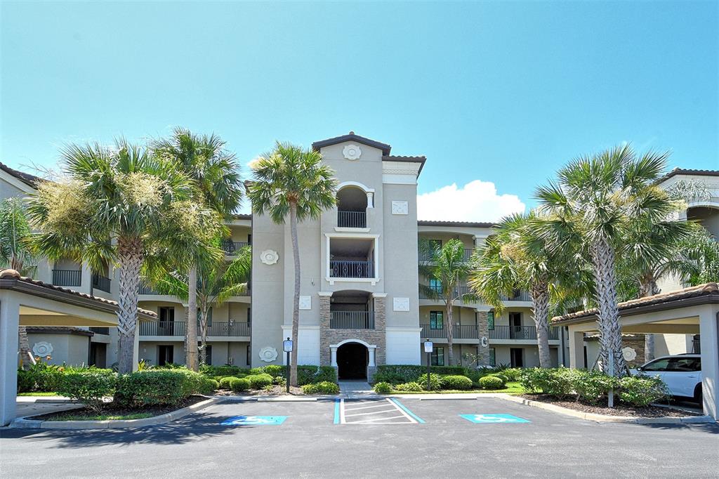A multi-story apartment building with a parking lot featuring accessible spaces in the foreground — 17006 VARDON TERRACE UNIT 305, BRADENTON, FL