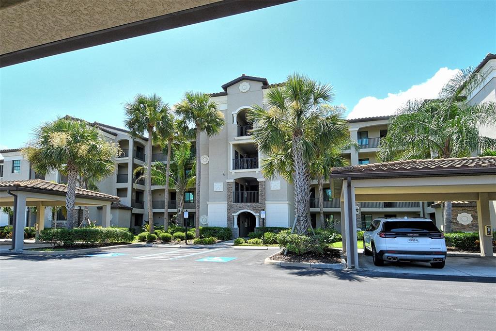 A multi-story apartment building with a covered parking area and palm trees in front — 17006 VARDON TERRACE UNIT 305, BRADENTON, FL