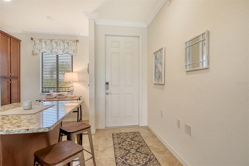 A kitchen with granite countertops, bar stools, and a white door leading to an entryway — 17006 VARDON TERRACE UNIT 305, BRADENTON, FL