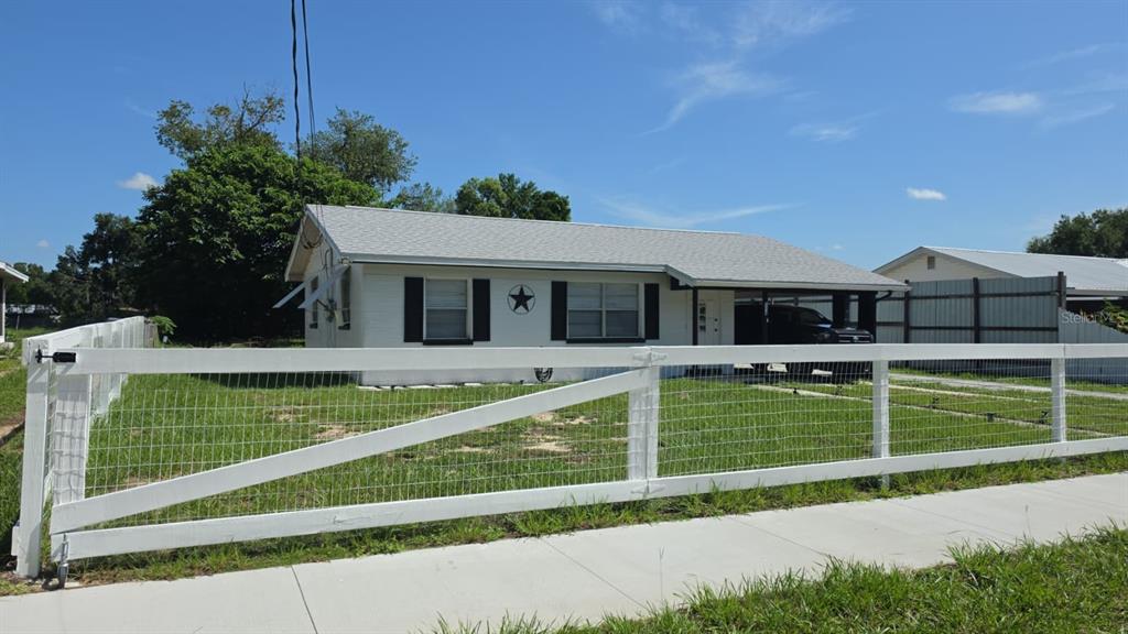 A white single-story house with a fenced front yard and a covered carport — 114 ANARECE AVENUE, AUBURNDALE, FL