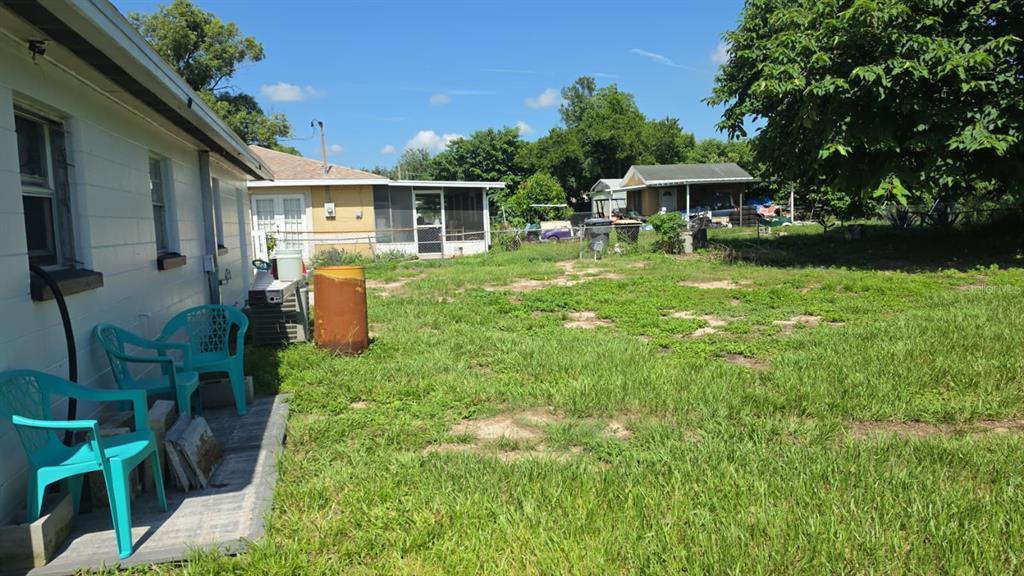 A backyard view showing a white house exterior, a patio with chairs, and a detached garage — 114 ANARECE AVENUE, AUBURNDALE, FL