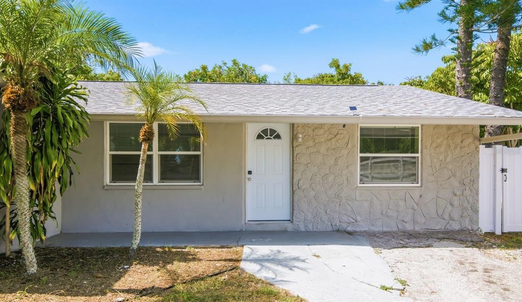 A single-story house exterior features a white front door, stone siding, and palm trees — 1119 17TH AVENUE SW, LARGO, FL