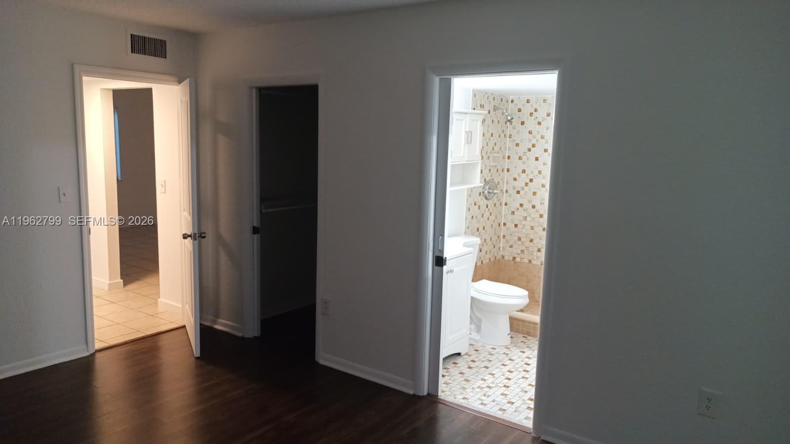 A room with dark wood flooring leads to a closet and a tiled bathroom — 8400 SW 133rd Ave Rd # 318, Miami FL 33183, MIAMI, FL