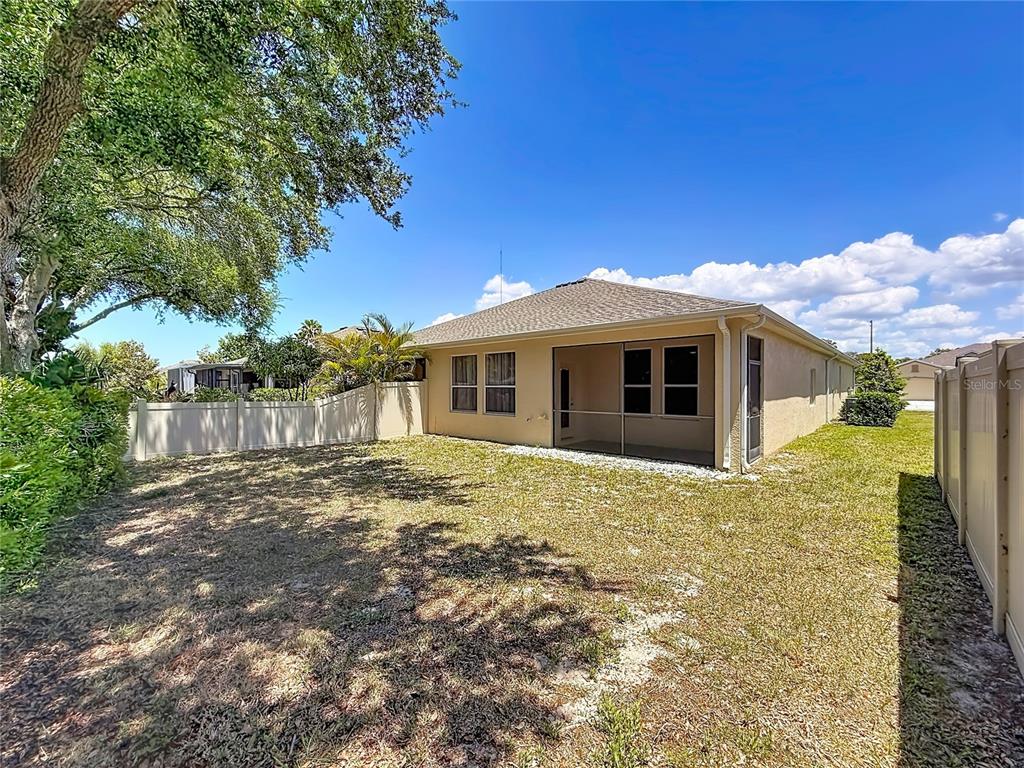 An aerial view shows a swimming pool with a covered patio area surrounded by trees — 1027 ORCA COURT, HOLIDAY, FL