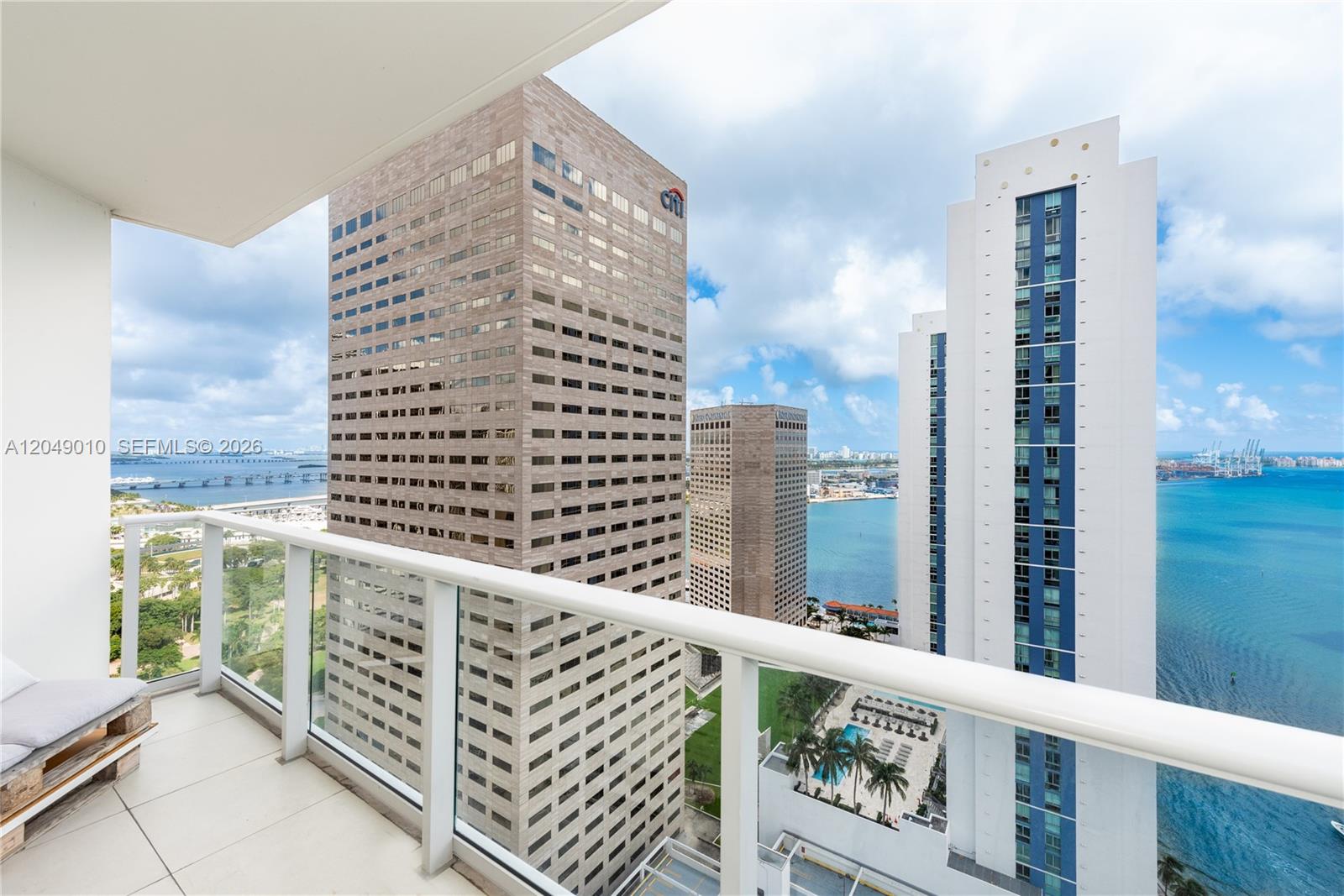 A balcony view overlooks high-rise buildings, a bay, and a bridge under a cloudy sky — 300 S Biscayne Blvd # 2814, Miami FL 33131, MIAMI, FL