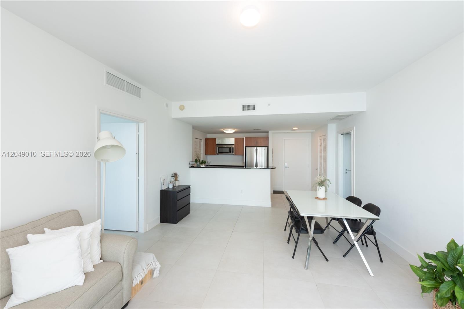 This open-concept living and dining area features white tile floors and a modern kitchen — 300 S Biscayne Blvd # 2814, Miami FL 33131, MIAMI, FL