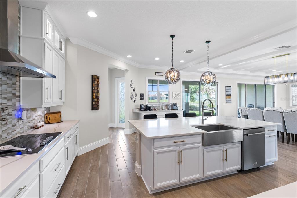 A modern kitchen features white cabinetry, a large center island with a sink, and tile flooring — 13352 ALDERLEY DRIVE, ORLANDO, FL