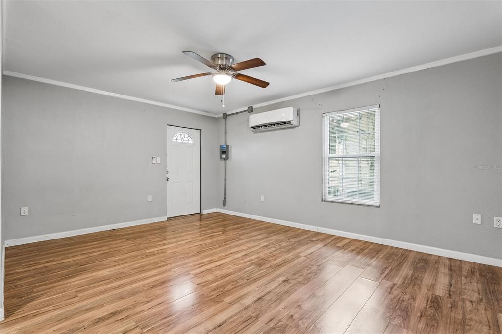 The exterior of a small, light-colored building features a window, an AC unit, and trees — 1408 HIGH STREET UNIT C, LEESBURG, FL