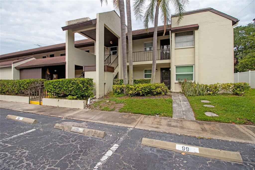A two-story apartment building with beige stucco walls, a brown roof, and palm trees — 1100 E BAY DRIVE UNIT 104, LARGO, FL