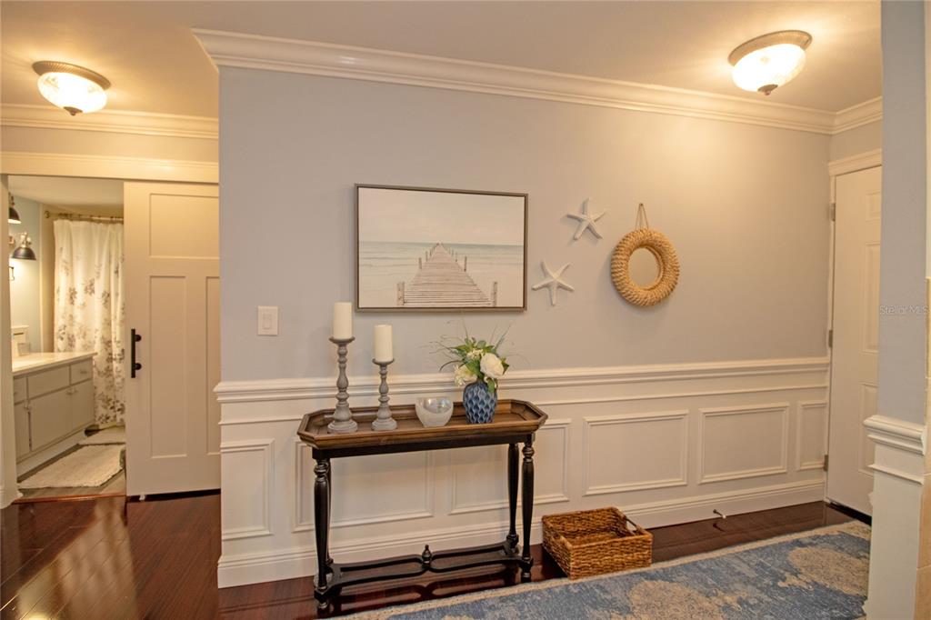 A hallway features wainscoting, a console table with decor, wall art, and a sliding door — 1100 E BAY DRIVE UNIT 104, LARGO, FL
