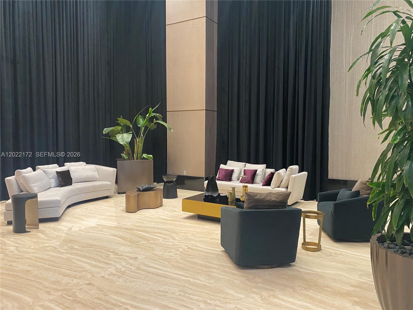 A spacious lobby features curved and linear sofas, dark armchairs, and tall black curtains — 950 Brickell Bay Dr # 2206, Miami FL 33131, MIAMI, FL