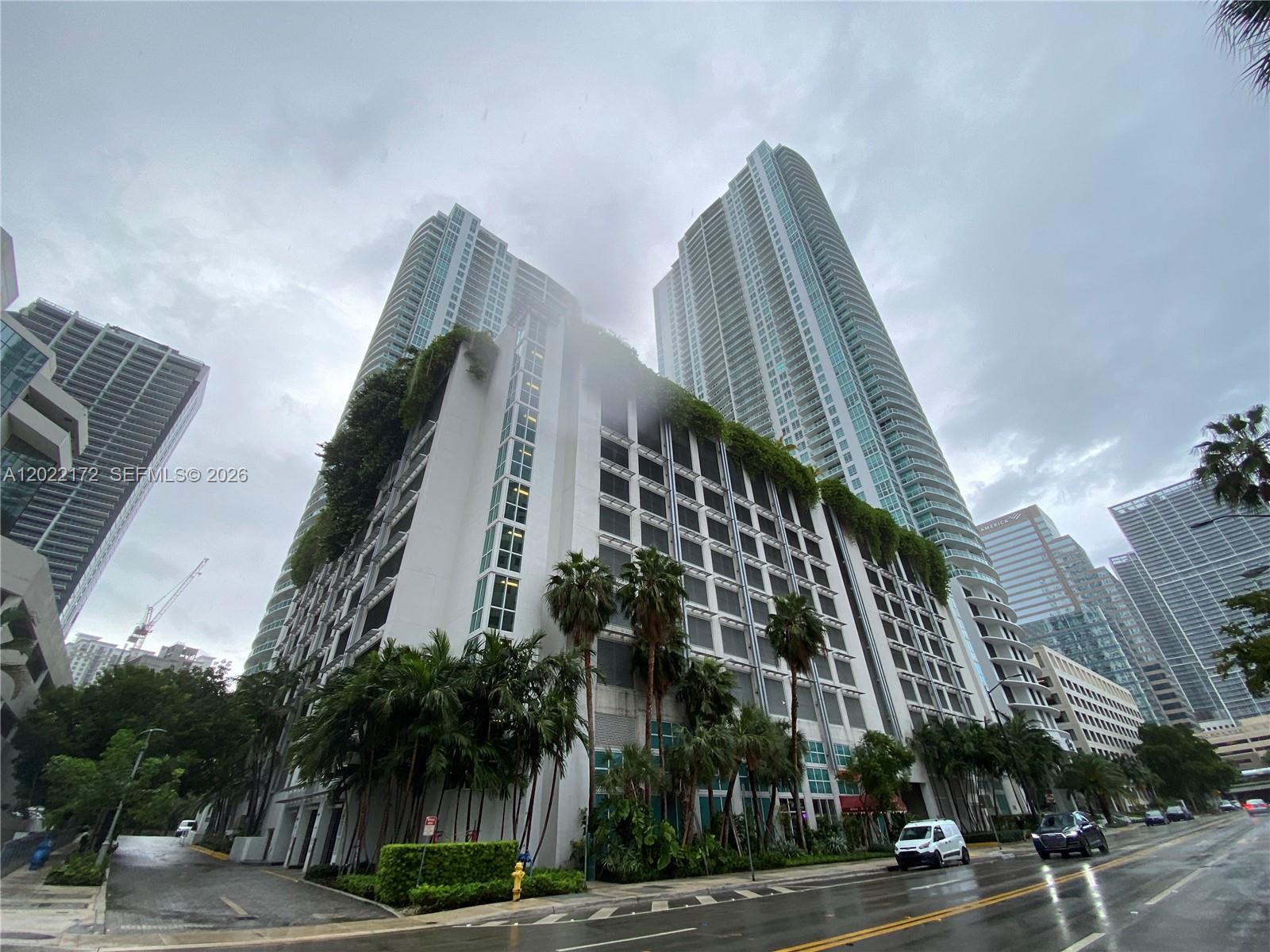 A low-angle view shows a tall residential building with a multi-level parking garage base — 950 Brickell Bay Dr # 2206, Miami FL 33131, MIAMI, FL