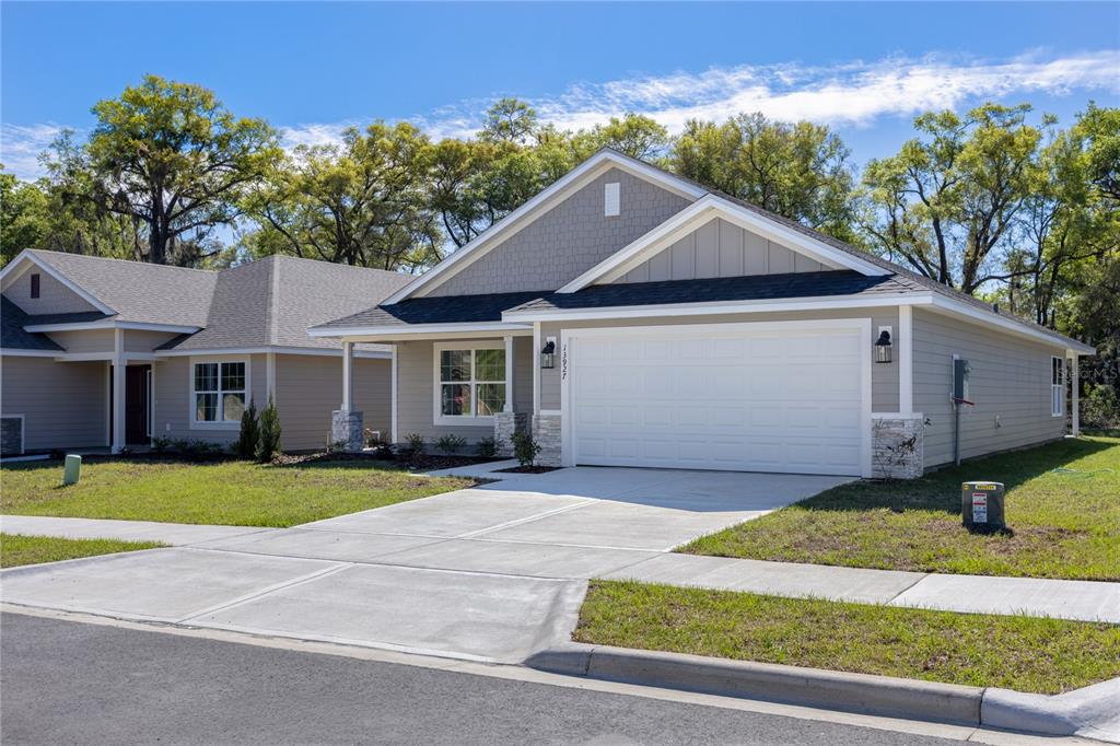 A single-story suburban house with a two-car garage, gray siding, and a concrete driveway — 13651 NW 150TH CIRCLE, ALACHUA, FL