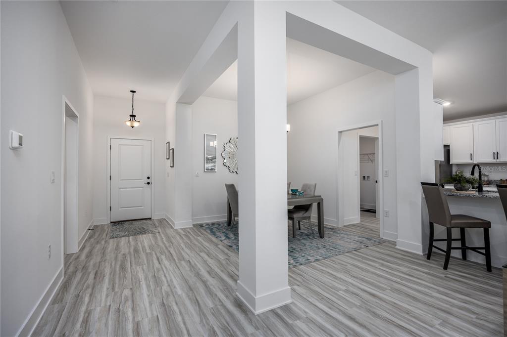 A bright entryway leads to a dining area and kitchen with light wood-look flooring — 13651 NW 150TH CIRCLE, ALACHUA, FL