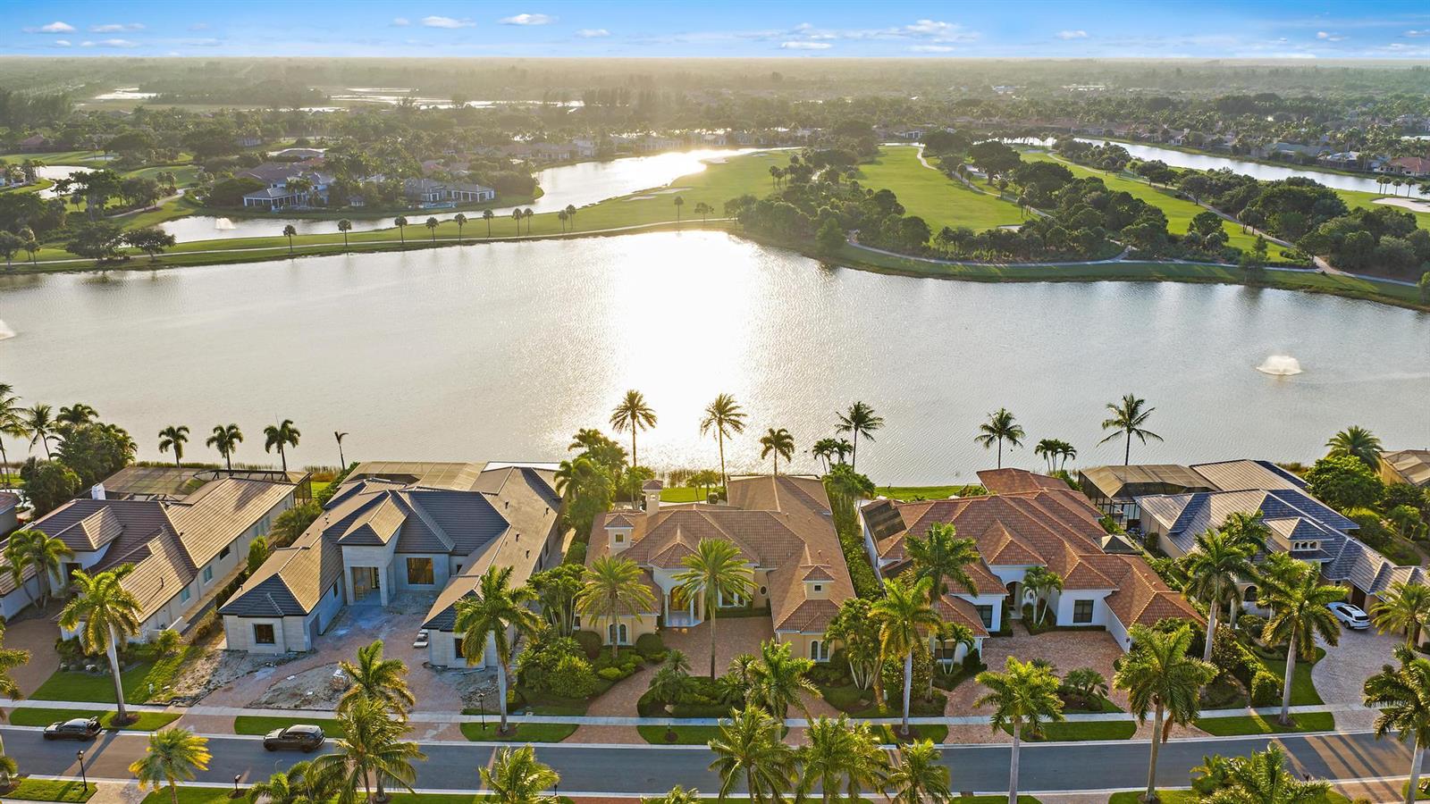 An aerial view shows several luxury houses with tiled roofs situated along a large lake — 7287 Horizon Drive, West Palm Beach FL 33412, WEST PALM BEACH, FL