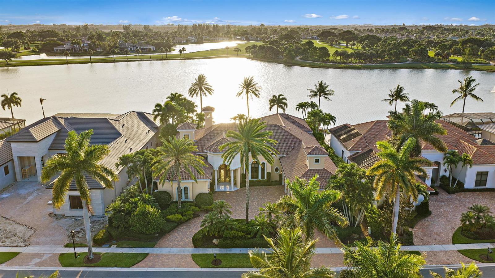 An aerial view of a luxury house with a tiled roof, palm trees, and lakefront — 7287 Horizon Drive, West Palm Beach FL 33412, WEST PALM BEACH, FL