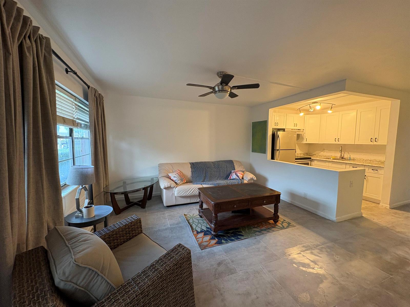 A living room with tile floors, a ceiling fan, and an open kitchen pass-through window — 2 Kent A, West Palm Beach FL 33417, WEST PALM BEACH, FL