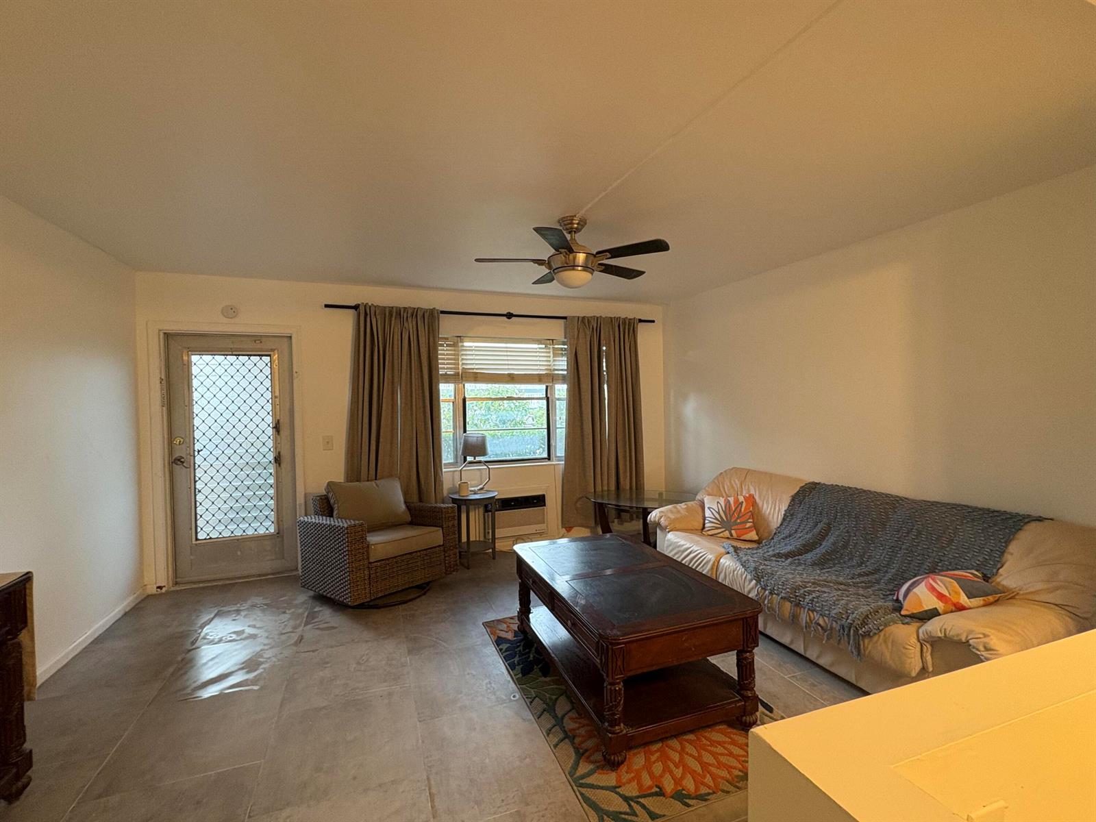 A living room features tile flooring, a ceiling fan, a sofa, and a glass-paneled door — 2 Kent A, West Palm Beach FL 33417, WEST PALM BEACH, FL