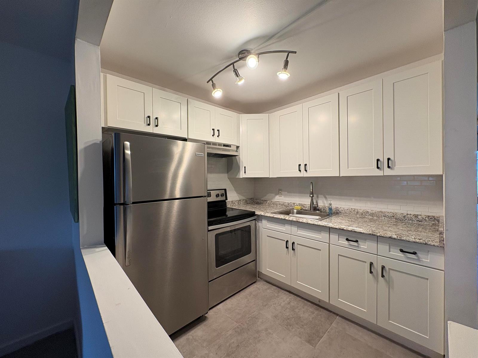 A kitchen featuring white cabinets, stainless steel appliances, granite countertops, and tile flooring — 2 Kent A, West Palm Beach FL 33417, WEST PALM BEACH, FL