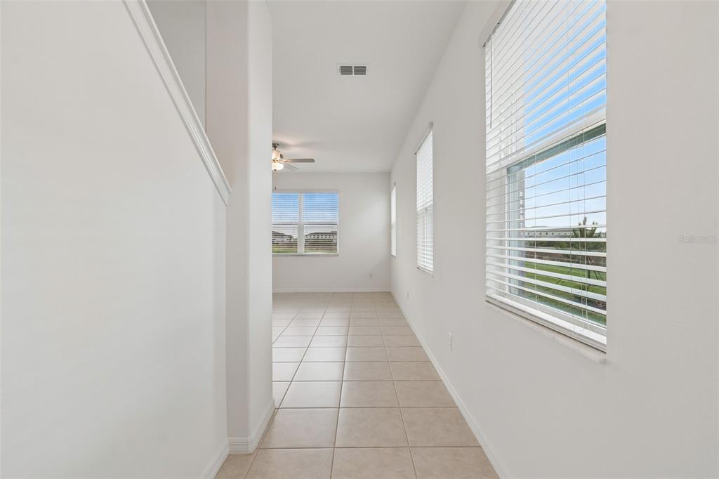 A bright hallway with light tile flooring leads to an open room with large windows — 32076 POP ASH PLACE, SAN ANTONIO, FL